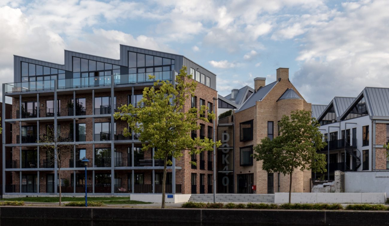 Waterfront nieuwbouw met bakstenen gevels, grote ramen en bomen langs de kade — Ontwikkeling DOK40 Eindhoven
