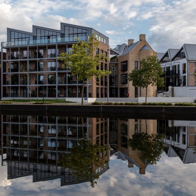 Waterfront nieuwbouw met bakstenen gevels, grote ramen en bomen langs de kade — Ontwikkeling DOK40 Eindhoven