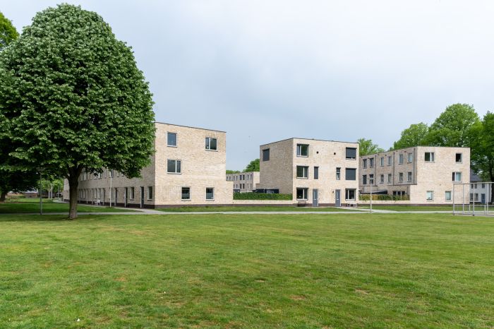 “Lichte bakstenen woonblokken rond groot grasveld met solitaire boom — Ontwikkeling De Vijf van Vorst Eindhoven
