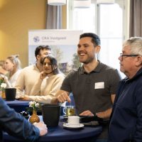 Bezoekers van de bijeenkomst in gesprek tijdens de start bouw van Bosrijk Mariëndaal; informele sfeer met koffie en informatiepanelen op de achtergrond.