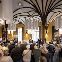 Start bouw Bosrijk Mariëndaal in velp: volle zaal luistert naar openingsspeech tijdens startbijeenkomst.