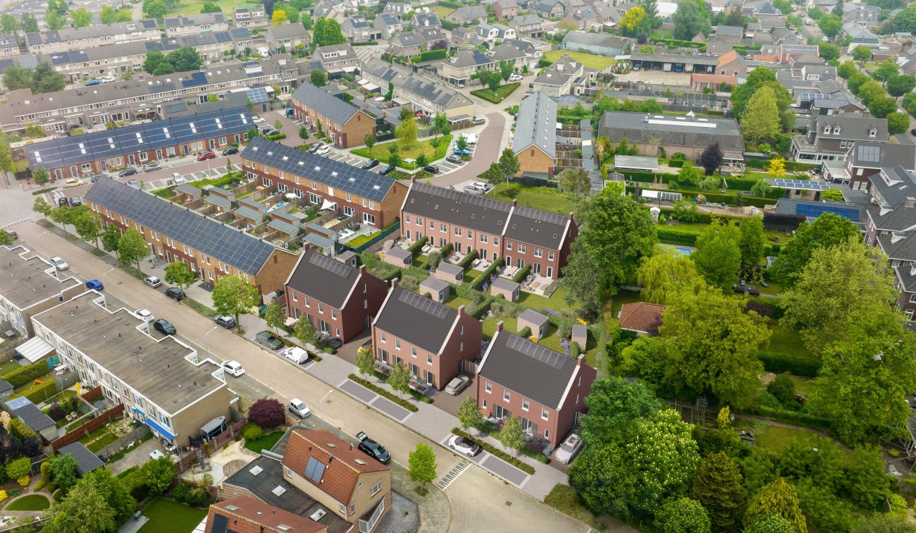Luchtfoto van een woonwijk in Valkenswaard met in het midden een 3D-impressie van nieuwbouwproject Molensteen: drie bakstenen huizen met donkere zadeldaken en zonnepanelen, tuinen en parkeerplaatsen; op de achtergrond bestaande rijwoningen en veel groen.