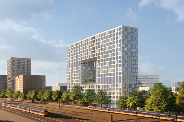 Impressie van woontorens Knoop XL Eindhoven – iconische toren met grote uitsparing en strak gevelraster, gelegen naast het spoor met passerende treinen en omringd door groen.