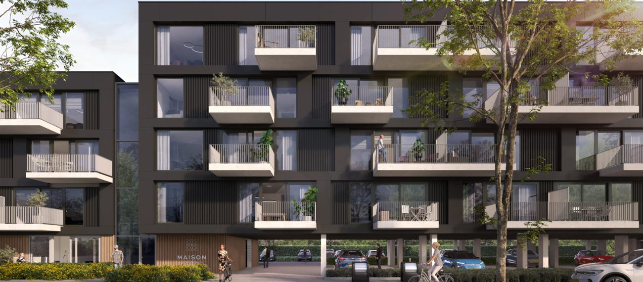 Close-up van Maison L’Europe in Helmond: modern donker appartementencomplex met uitstekende witte balkons en grote ramen, op kolommen met doorgang naar de parkeergarage; bomen, een fietser en voetgangers op de voorgrond.