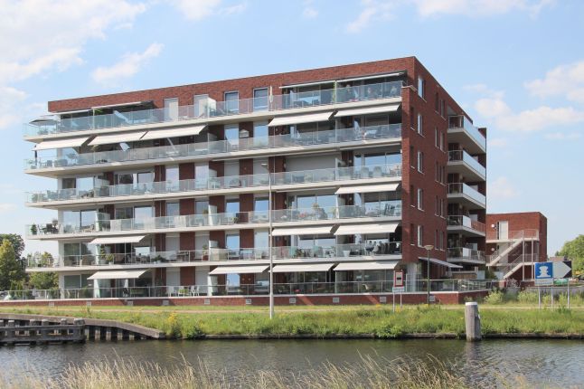 Nieuwbouwcomplex op het HIVA-terrein in Son, gezien vanaf het water, met zicht op de moderne architectuur en de waterkant.