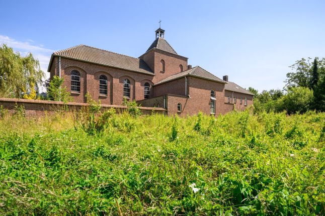 Historisch kloostergebouw in Eindhoven met rondboogvensters, gezien vanaf weide — Transformatie Clarissenklooster Eindhoven