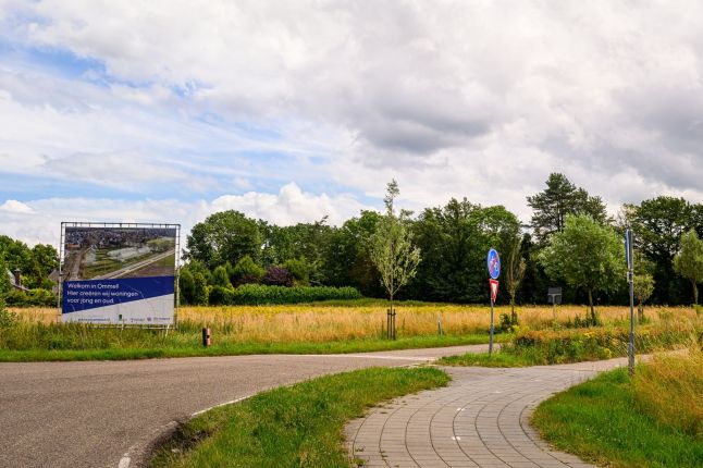 Toekomstige bouwlocatie aan rand van Ommel met aankondigingsbord en grasland — Ontwikkeling Kluisstraat Ommel
