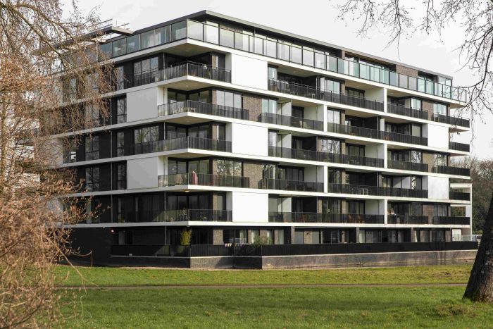 Woongebouw met doorlopende galerijen, donkere baksteen en veel glas, gezien vanaf groenstrook — Ontwikkeling Het Schrijverskwartier Eindhoven