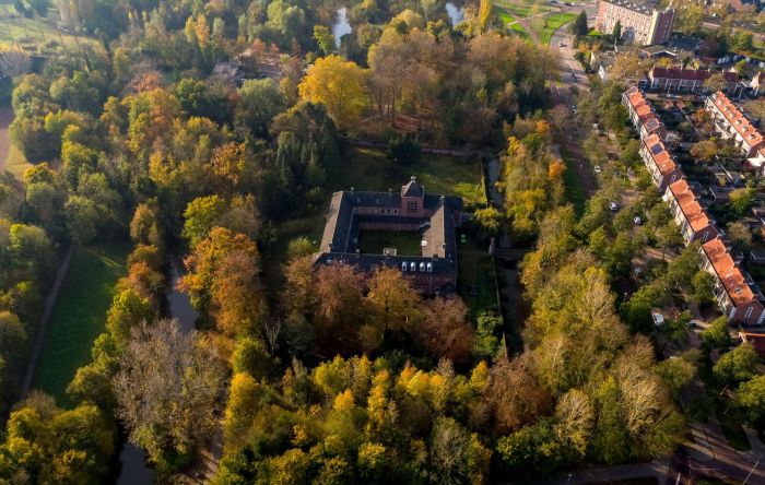 Luchtfoto Clarissenklooster omgeven door herfstbos en waterlopen aan stadsrand — Transformatie Clarissenklooster Eindhoven