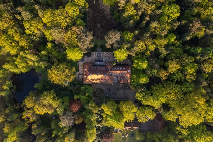 Top-down luchtfoto: historisch landhuis met binnenhof en terrassen tussen groene boomkronen — Ontwikkeling Landgoed De Utrecht Esbeek