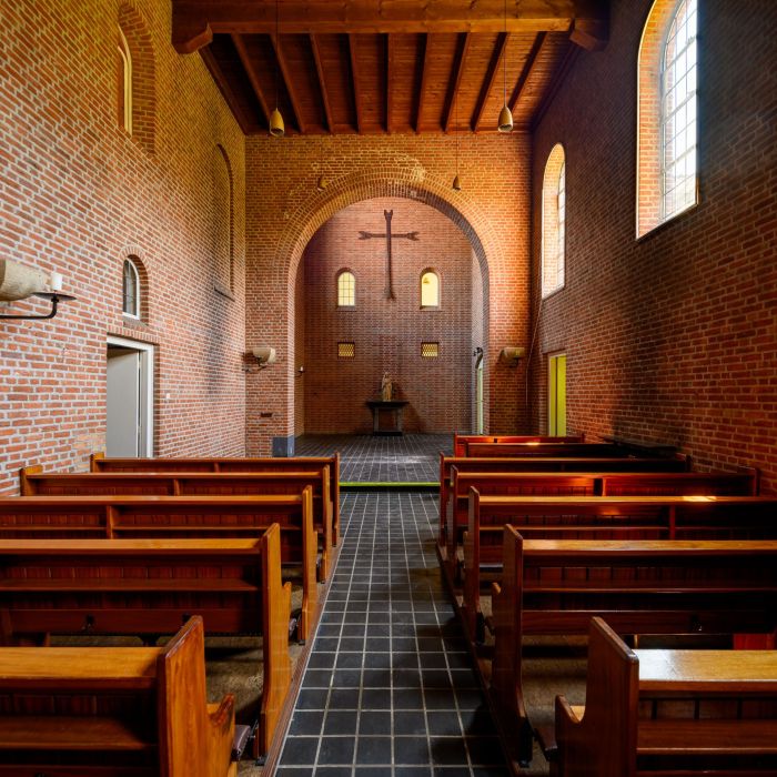 Kloosterkapel met houten banken, bakstenen tongewelf en kruis in de apsis — Transformatie Clarissenklooster Eindhoven