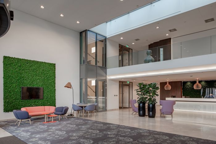 Entreehal met glazen lift, mezzanine en moderne receptie, planten en sfeerverlichting — Ontwikkeling Dorgelo Building Eindhoven