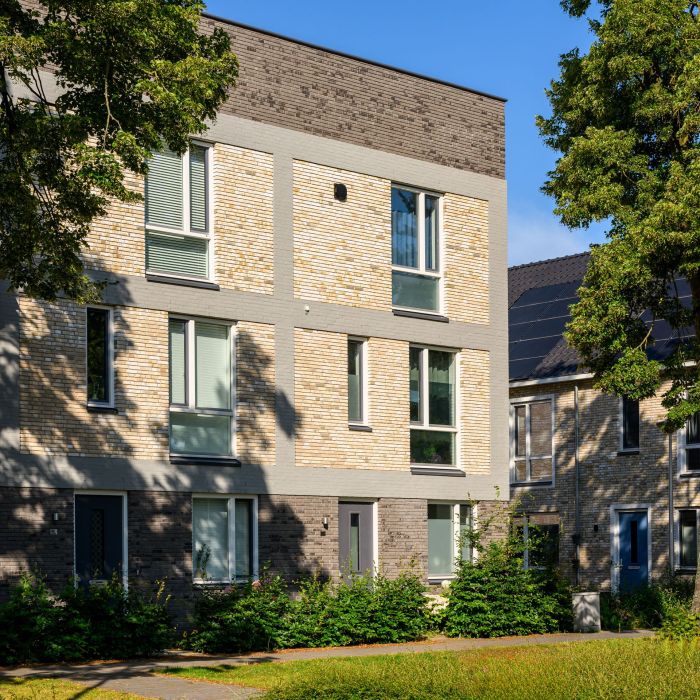 Moderne stadswoning met reliëf metselwerk, smalle raamstroken en groen aan de gevel — Ontwikkeling De Vijf van Vorst Eindhoven