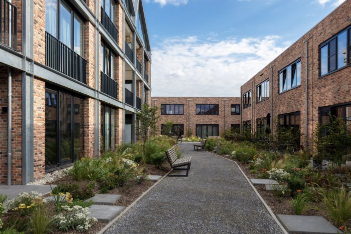 Binnentuin van nieuwbouwproject DOK40 in Eindhoven, met beplanting, zitplekken en uitzicht op de omliggende woningen en appartementen.