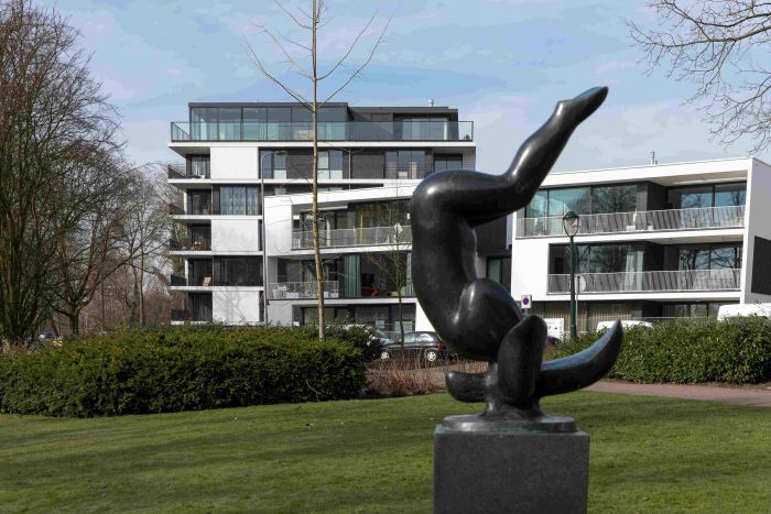 Kunstwerk op sokkel op groen plantsoen, hedendaagse woonblokken op achtergrond — Ontwikkeling Het Schrijverskwartier Eindhoven