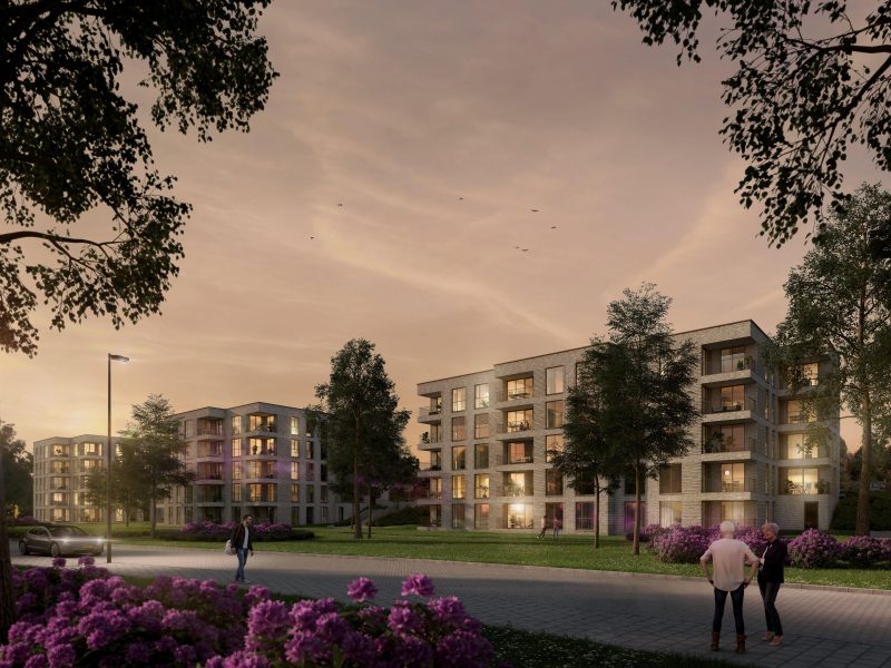 Impressie van moderne appartementencomplexen omringd door groen en bloeiende struiken tijdens zonsondergang, met wandelende mensen op de voorgrond.